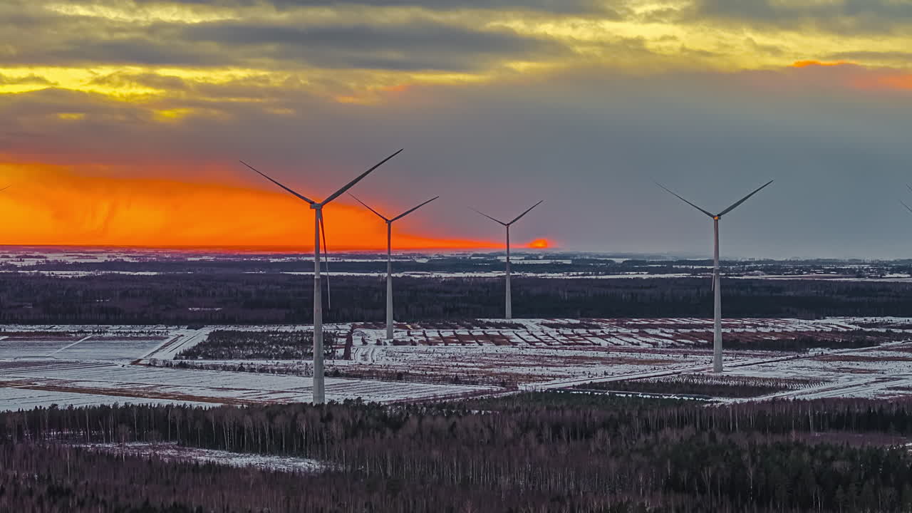 Vindmøller på snedækkede marker ved solnedgang – en fredfyldt og bæredygtig scene.