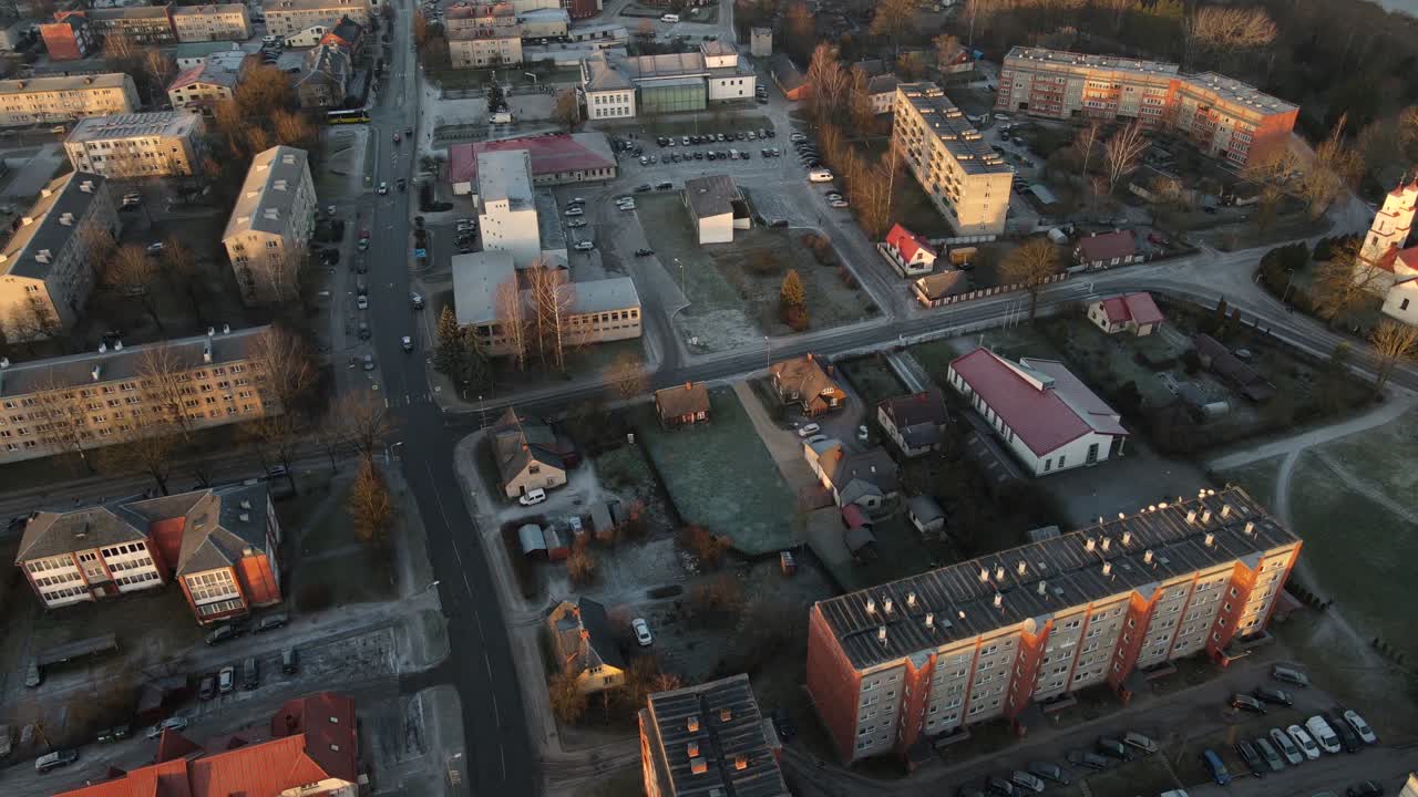 аэрофотографа города балви, купающегося в теплом свете заката, с городскими зданиями, парковками и снежным пейзажем. мирная зимняя сцена.