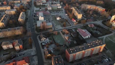 foto aérea de la ciudad de balvi bañada en la cálida luz del atardecer, con edificios urbanos, estacionamientos y un paisaje cubierto de nieve. una escena de invierno pacífica.