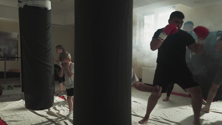 Kids and adult sportsmen train in kickboxing club together. Skilled and little fighters exercise with punching equipment in martial arts gym. Sports for different generations