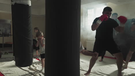 kids and adult sportsmen train in kickboxing club together. skilled and little fighters exercise with punching equipment in martial arts gym. sports for different generations