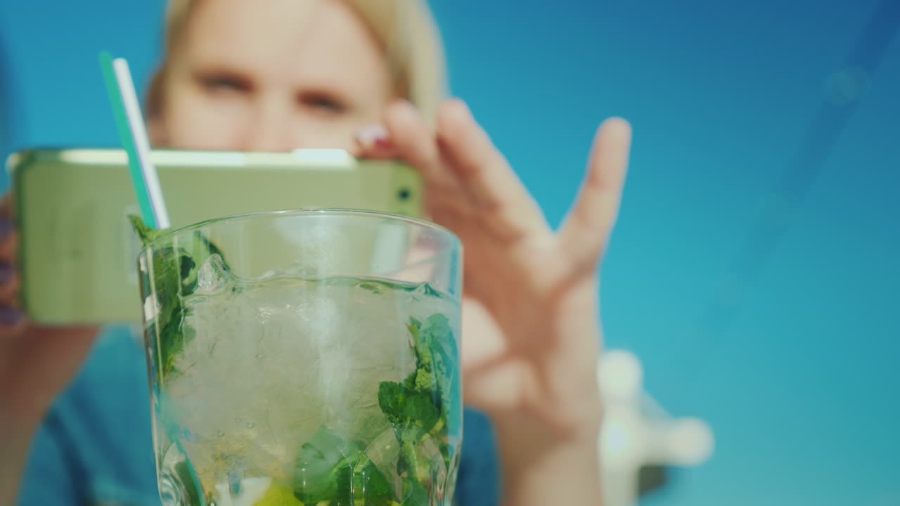 여성 블로거가 칵테일 레스토랑 평론가와 함께 잔을 촬영하고 있습니다.