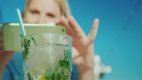 a woman blogger is photographing a glass with a cocktail restaurant critic