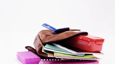 schoolbag with various supplies on white background