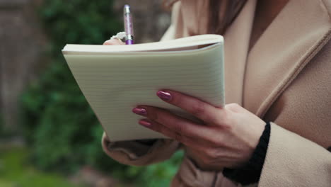 details of a woman hands outdoor taking notes on the notebook