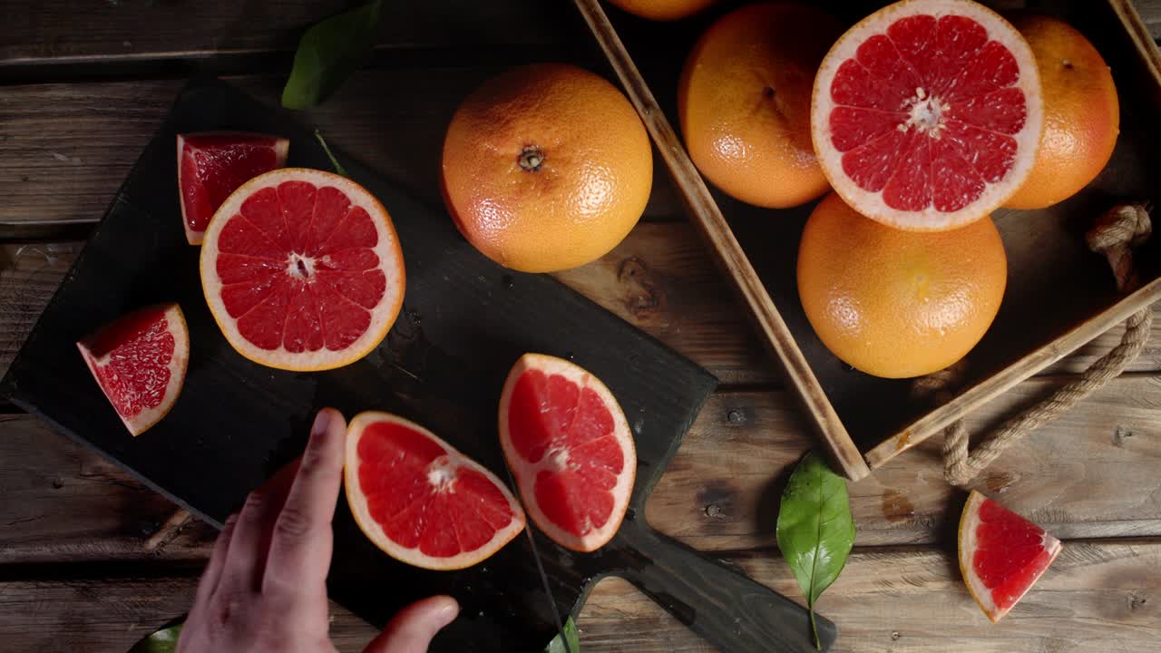 Hands men cut the grapefruit on a cutting Board.