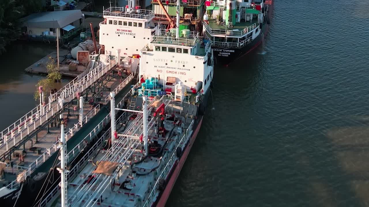 Work on cargo ship near riverside in Bangkok with cranes and equipment
