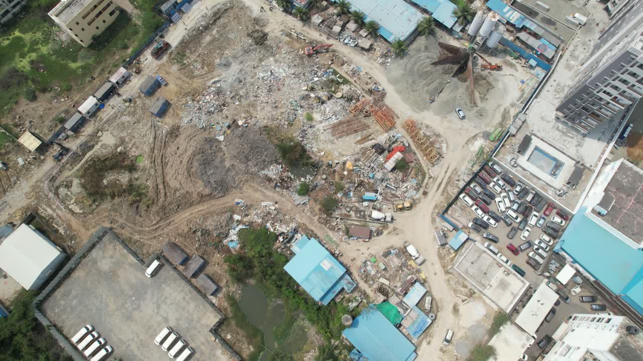 un patio de salvamento lleno de automóviles, tierra, acero y bloques de cemento