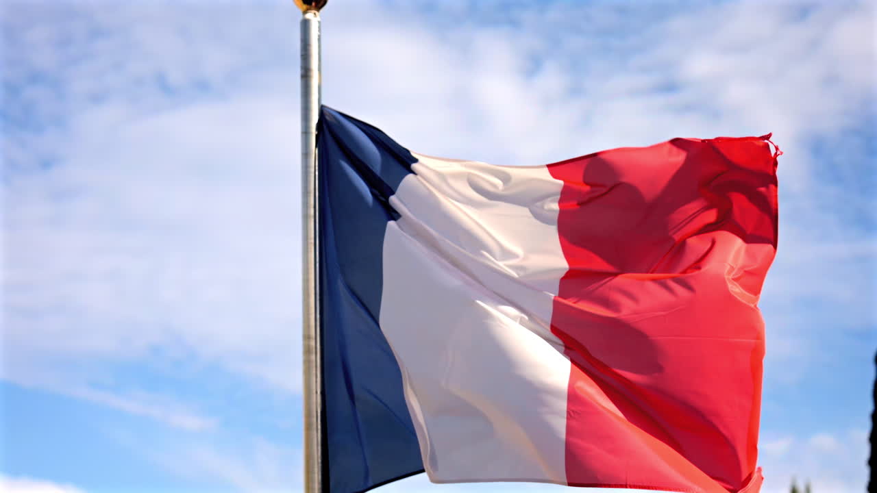 Close up of the flag of France waving in the wind with a blue sky on the background