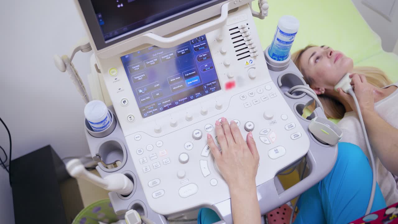Modern medical equipment in the hospital. Female specialist makes ultrasound scanning diagnostic of thyroid gland to a woman in clinic.