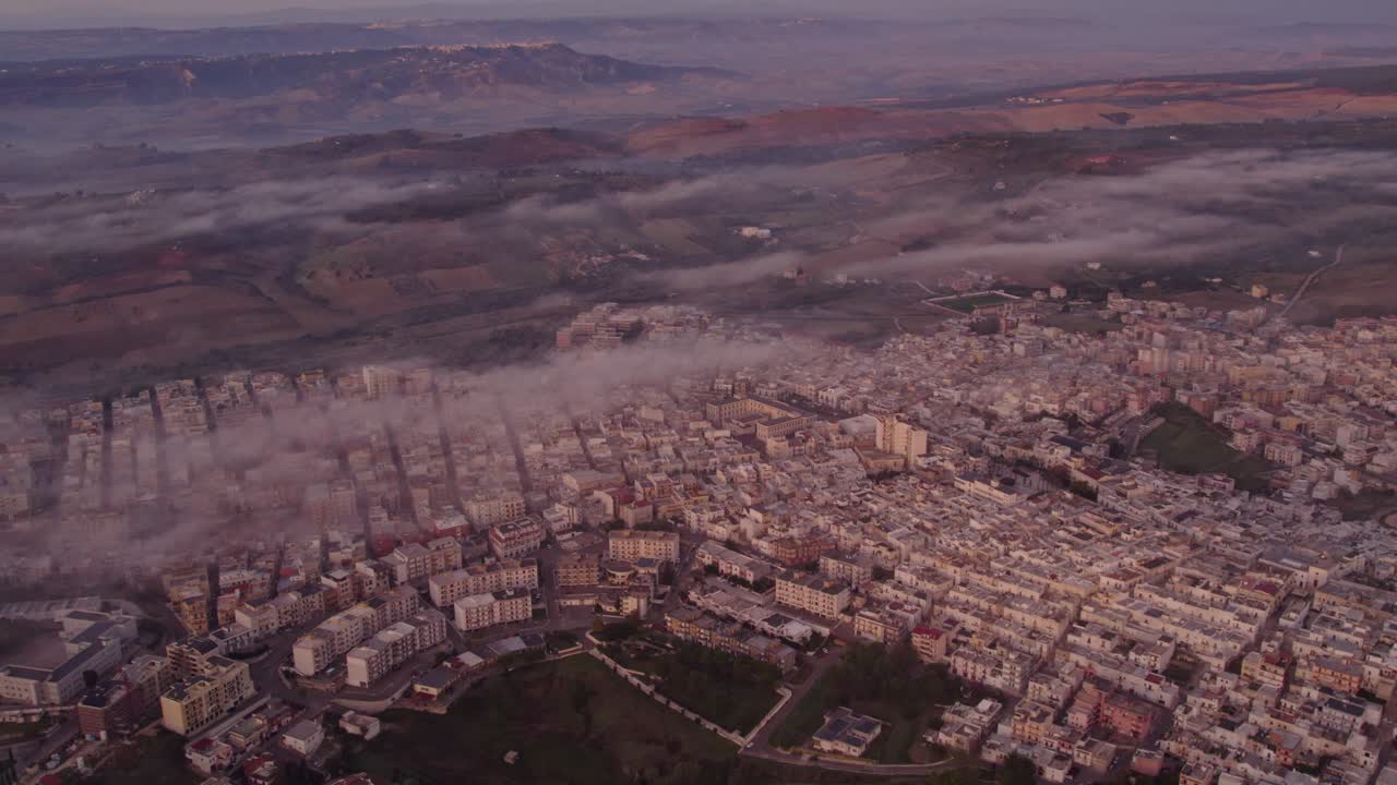 Alba dorata illumina una città tranquilla sotto una soffice coltre di nuvole