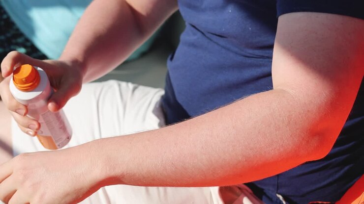 person, die sich im freien sonnencreme auf den arm legt