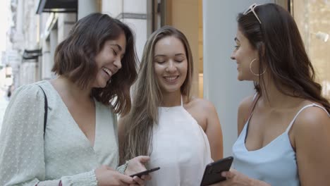 happy best female friends using smartphones together