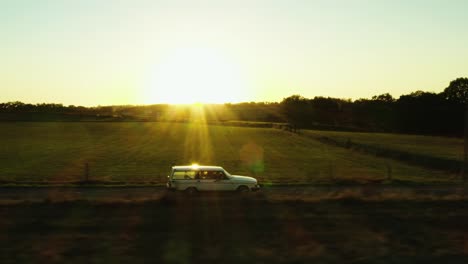 Cinematic-aerial-shot-of-Volvo-driving-through-France-landscape,-trees,-roads-and-villages