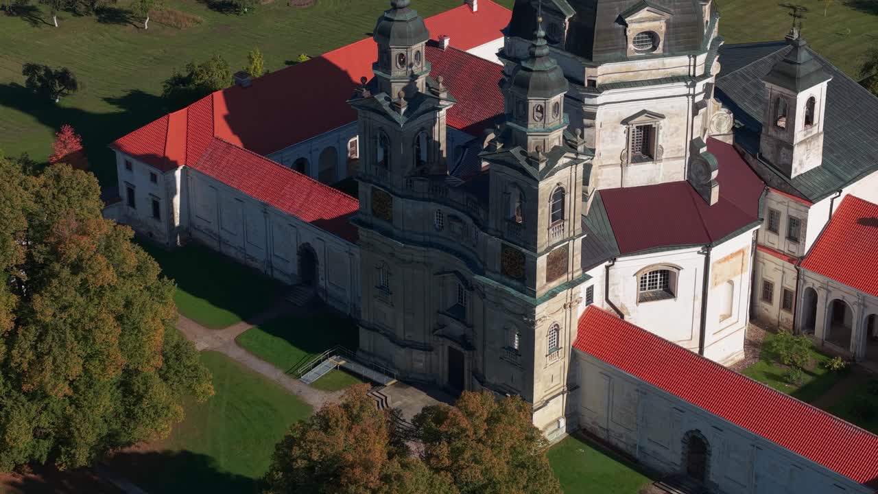 Close-up aerial view of Pažaislis Monastery in Kaunas, Lithuania, showcasing its impressive Baroque towers, dome, and detailed architecture surrounded by autumn-colored trees