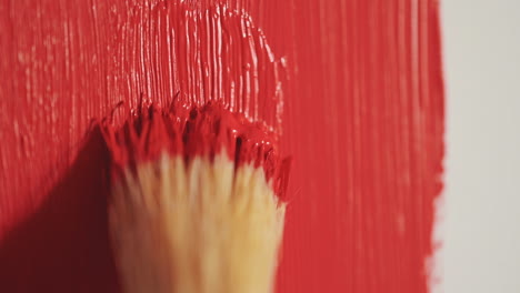 detalle de un pincel pintando en rojo un lienzo