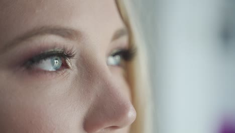 sensitive, dreamy, sad and thoughtful blue eyes of blond women looking out of window - cinematic close up macro shot