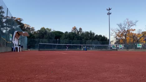 Vista-Lateral-Amplia-Joven-Jugadora-De-Tenis-Caucásica-Adolescente-Sirviendo-Durante-Un-Juego-O-Práctica