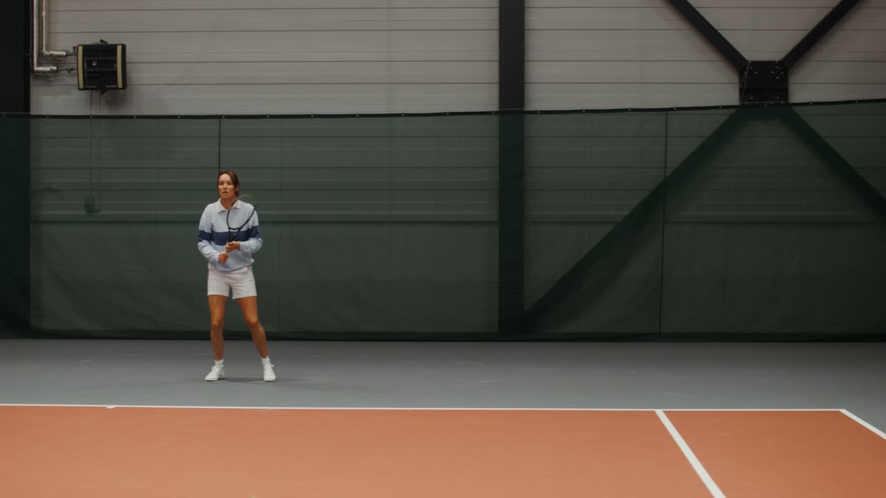 실내 코트에서 테니스를 하는 여자