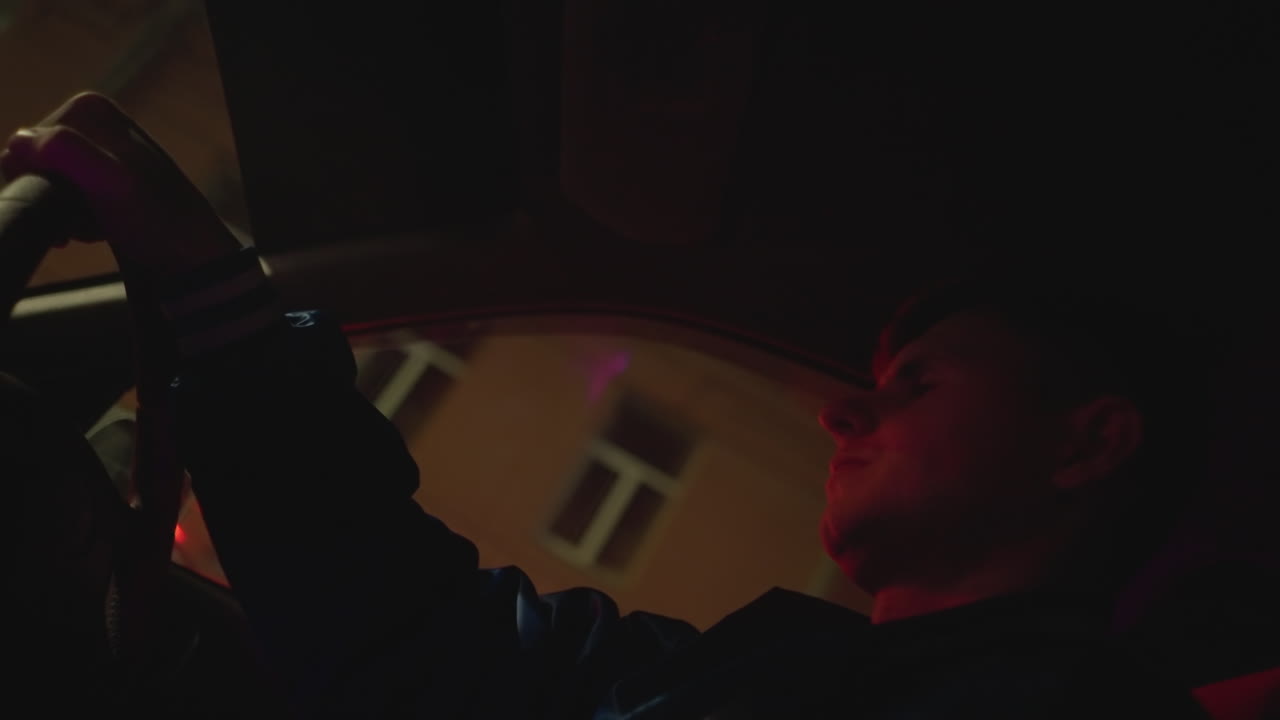 Tranquillo viaggio urbano con autista contemplativo, silenzioso giro notturno per le vie della città con autista riflessivo, sereno giro di mezzanotte con autista premuroso illuminato dal bagliore rosso dei neon