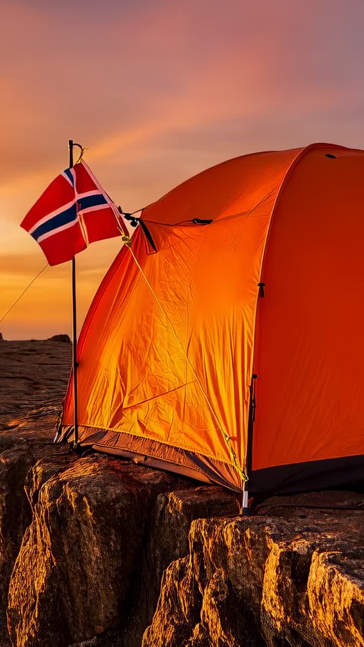 Vertikal video: Visar orangefärgat tält på klippavsats, norsk flagga som vajar i vinden, himlen blir mörkare