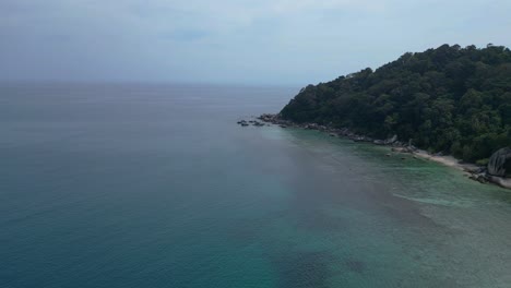 agua turquesa lavando suavemente una playa de arena rodeada de rocas de granito y exuberante vegetación tropical
