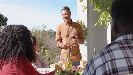 happy caucasian man toasting on thanksgiving celebration meal in sunny garden