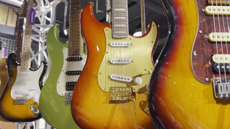 close-up of colorful electronic guitars hanging on the wall of a shop. a collection of bass guitars. vertical video.