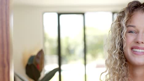 Half-portrait-of-happy-caucasian-woman-with-curly-blonde-hair-smiling,-copy-space,-slow-motion