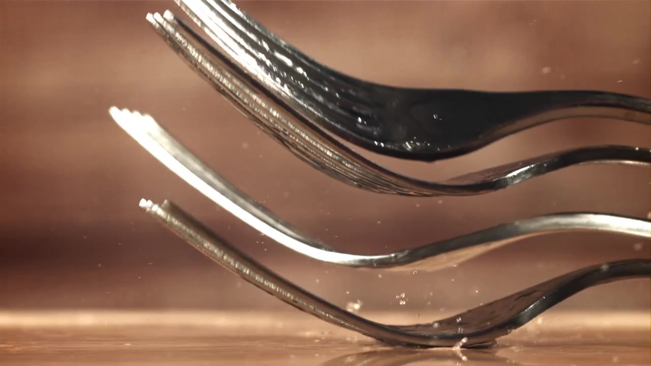 Slow Motion Close Up of Metallic Forks Falling and Stacking