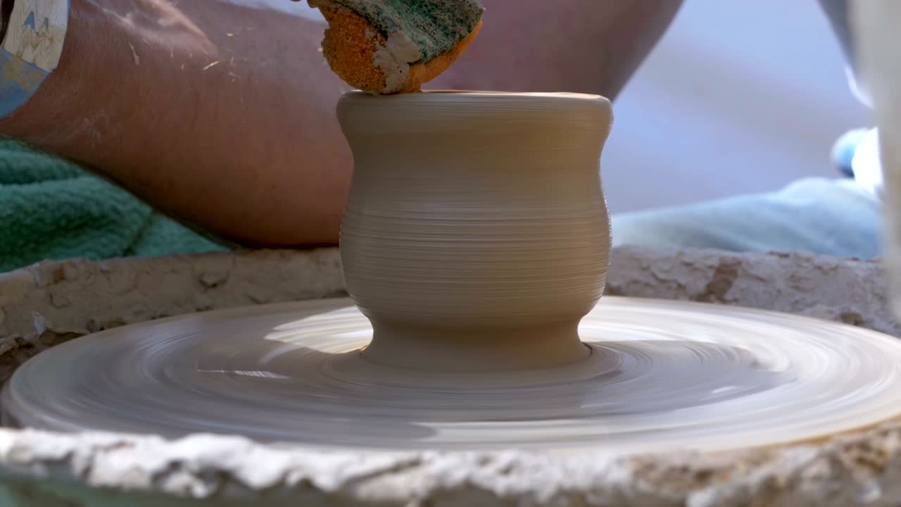 Mani del maestro vasaio e vaso di argilla sul tornio da vasaio