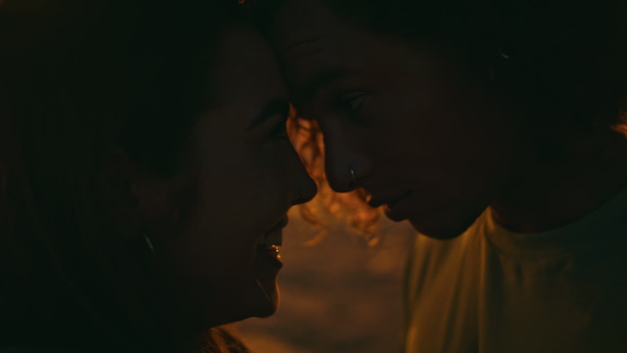 십대 연인 실루이 야간 해변에서 결합합니다. 젊은 남자가 속삭이고 있습니다.