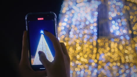 Una-Chica-Graba-Un-Vídeo-De-Las-Luces-Navideñas-Con-Su-Teléfono-Inteligente-En-Cámara-Lenta.