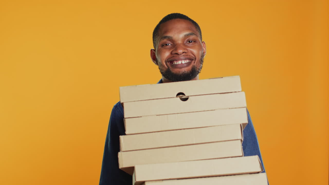 Confident male courier carrying big pile of pizza boxes to deliver fast food order