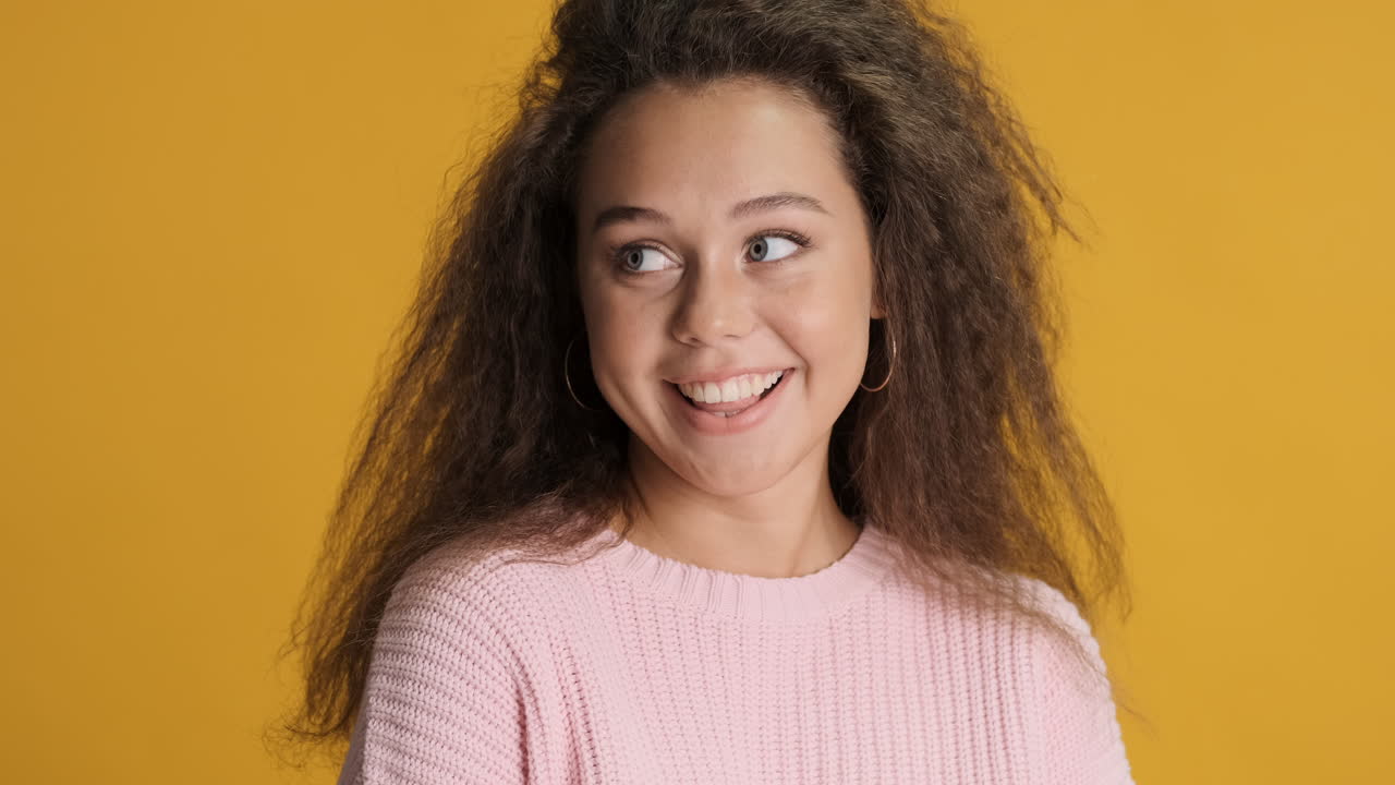 una mujer caucásica de cabello rizado sonriendo a la cámara.