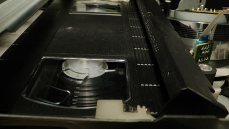 old video recorder inside close-up, vhs. retro player in neon blue light, vintage video cassette broadcasting, audio tape.