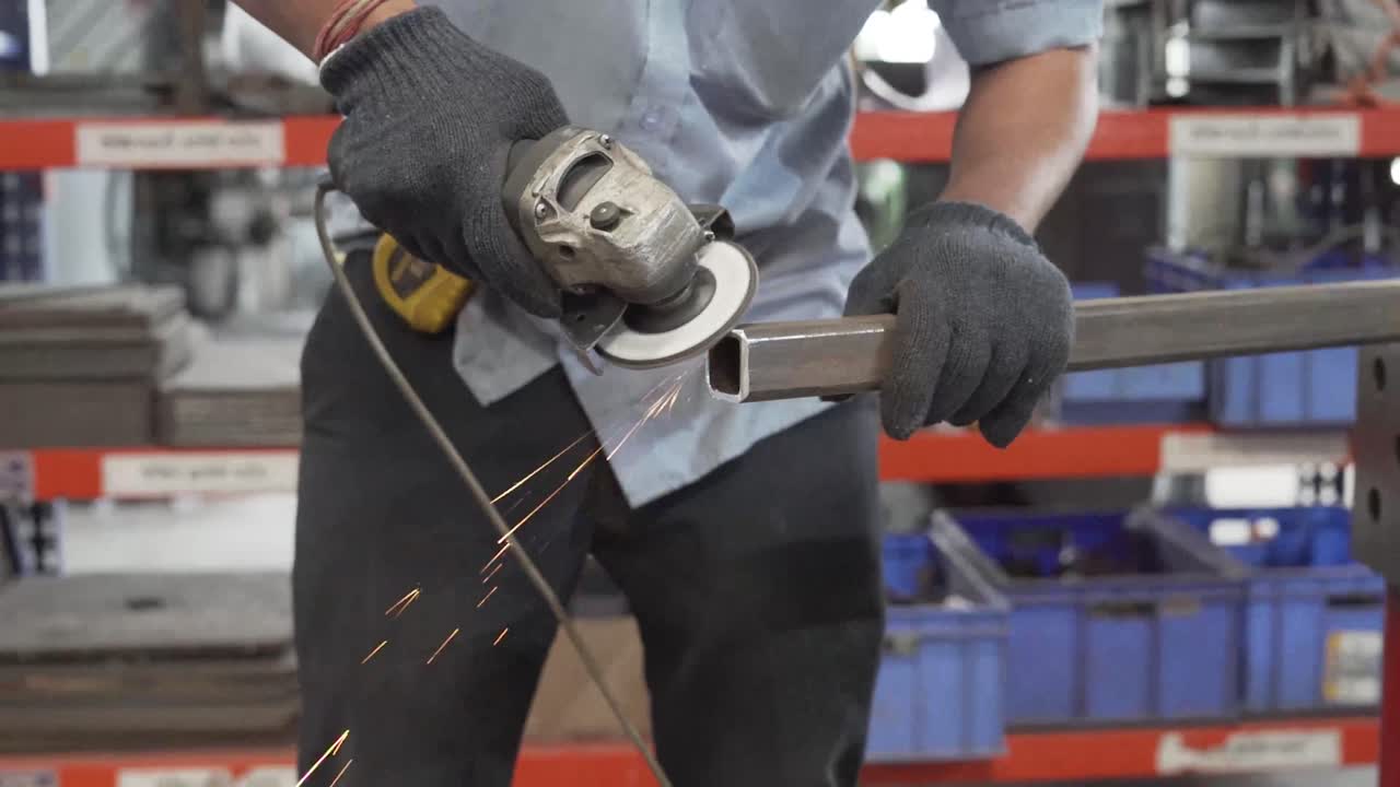 Asian man grinding a square metal pole. Smoothening the surface using a grinder