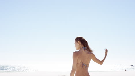 beautiful-young-woman-tying-up-hair-on-windy-day-on-tropical-beach-slow-motion