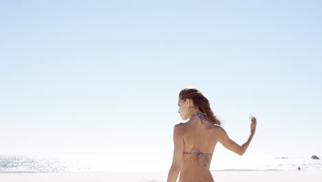 hermosa mujer joven atando el cabello en un día ventoso en una playa tropical en cámara lenta