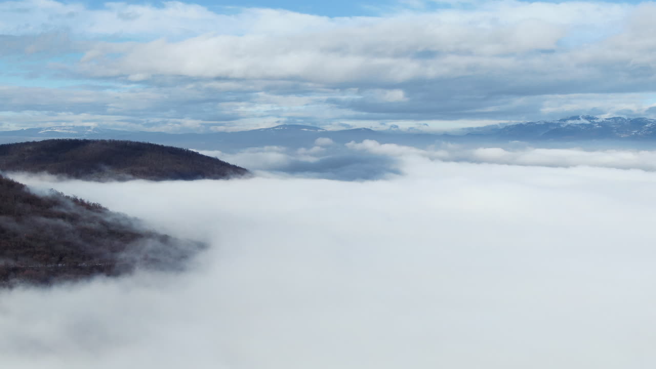 Landscape view with mountains clouds and sky Cloud cover visible over mountains with sky in the background White cloud cover is present in foreground