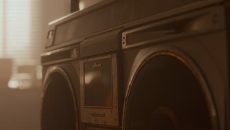 close-up of hand loading cassette tape into vintage boombox in soft warm light