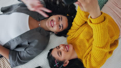 two friends taking selfies on bed
