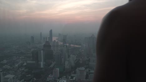 silhouette shot of a man looking onto the downtown view of bangkok