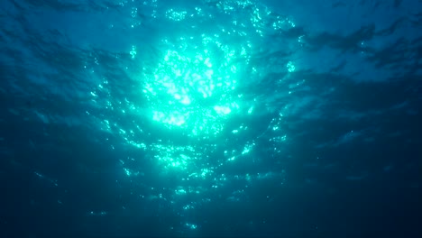 sun shining through ocean surface filmed from underneath the surface