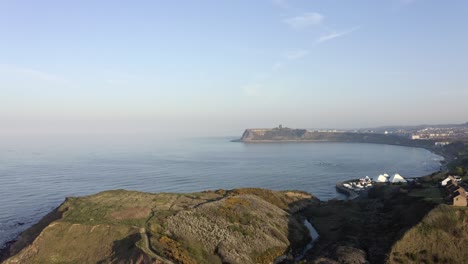 Luftschwenkansicht-Der-Küstenstadt-Mit-Klippenwohnungen,-Scarborough,-England,-Großbritannien