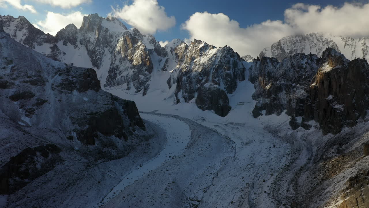 Lenta, epica ripresa cinematografica con drone di un ampio passaggio attraverso le montagne del ghiacciaio Ak-Sai in Kirghizistan