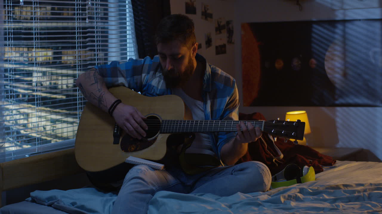 Man Playing Acoustic Guitar in Bedroom at Night