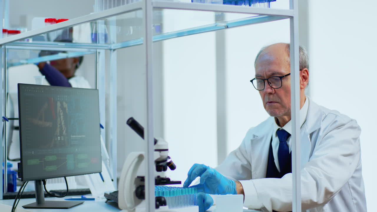 Elderly man scientist doing research analysing liquid in tube at laboratory