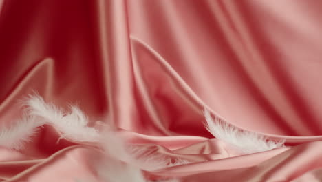 white feathers on pink satin