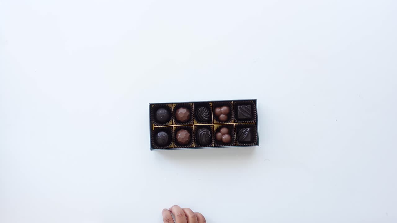 Child's hand reaching into a box of chocolates